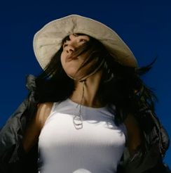Young woman in a white wide-brim hat and tank top under a deep blue twilight sky